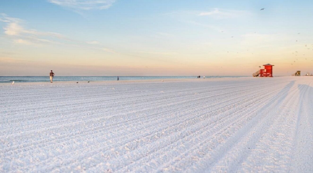 Une plage enneigée avec une tour de surveillance et une personne qui se promène.