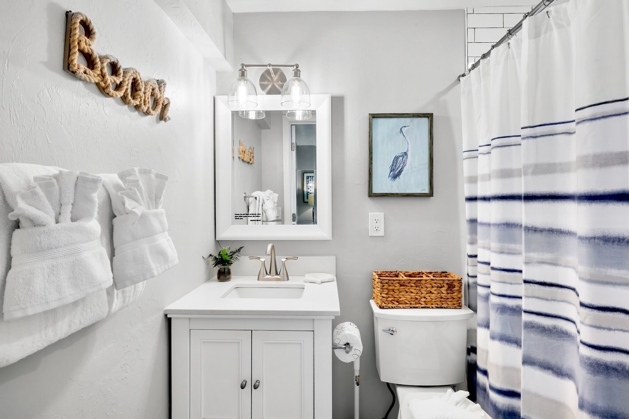 A bathroom with a white vanity, a mirror, a toilet, and a shower curtain.