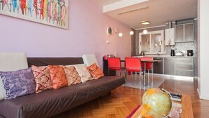 A modern living room with a brown sofa, a dining area with red chairs, and a kitchen with stainless steel appliances. - Historico Duplex en el Centro (Buenos Aires)
