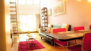 A cozy living room with a sofa, a dining table, and a bookshelf. - Historico Duplex en el Centro (Buenos Aires)