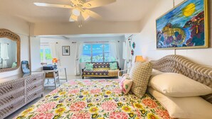 A bedroom with a bed, a desk, a chair, a dresser, and a window with curtains.