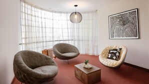 A modern living room with three armchairs, a round coffee table, and a large abstract painting on the wall. - Hotel San Felipe Suites (Arequipa)