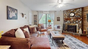 A cozy living room with a brown sofa, a coffee table, and a fireplace with a stone mantle.