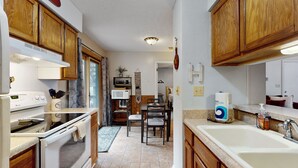 A compact kitchen with wooden cabinets, a built-in oven, a microwave, and a sink.