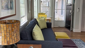 Un salon moderne avec un canapé bleu foncé, une table basse en bois et un tapis à motifs.