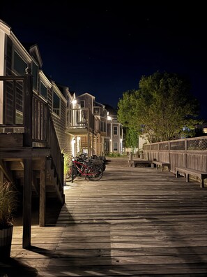 A wooden boardwalk leading to a row of houses with balconies, a bicycle parked on the boardwalk, and a tree to the right. - West End Studio in a Waterfront Building (Provincetown)