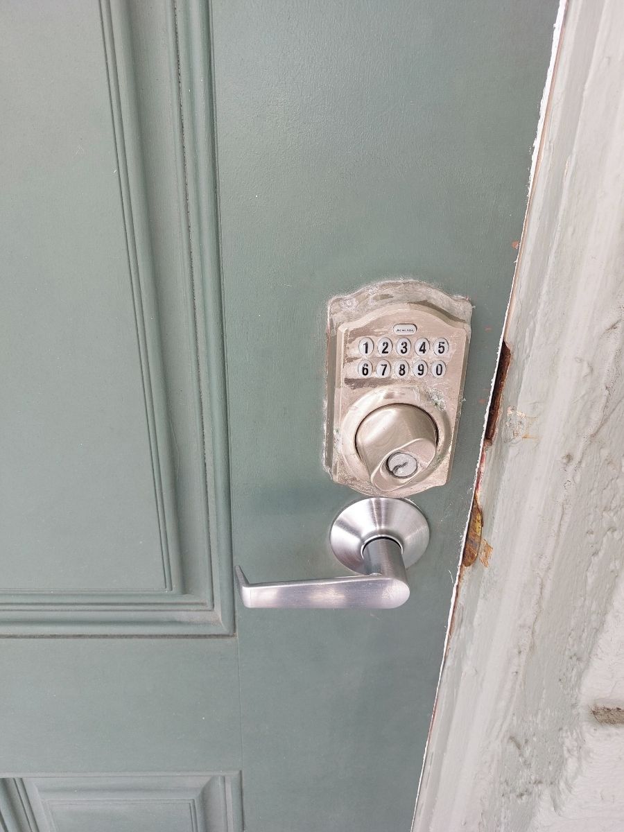 Uma porta com fechadura eletrônica e puxador prateado.