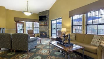 A living room with a fireplace, a television, and a large window with blinds.