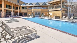 A hotel with a large pool, multiple balconies, and outdoor seating areas.