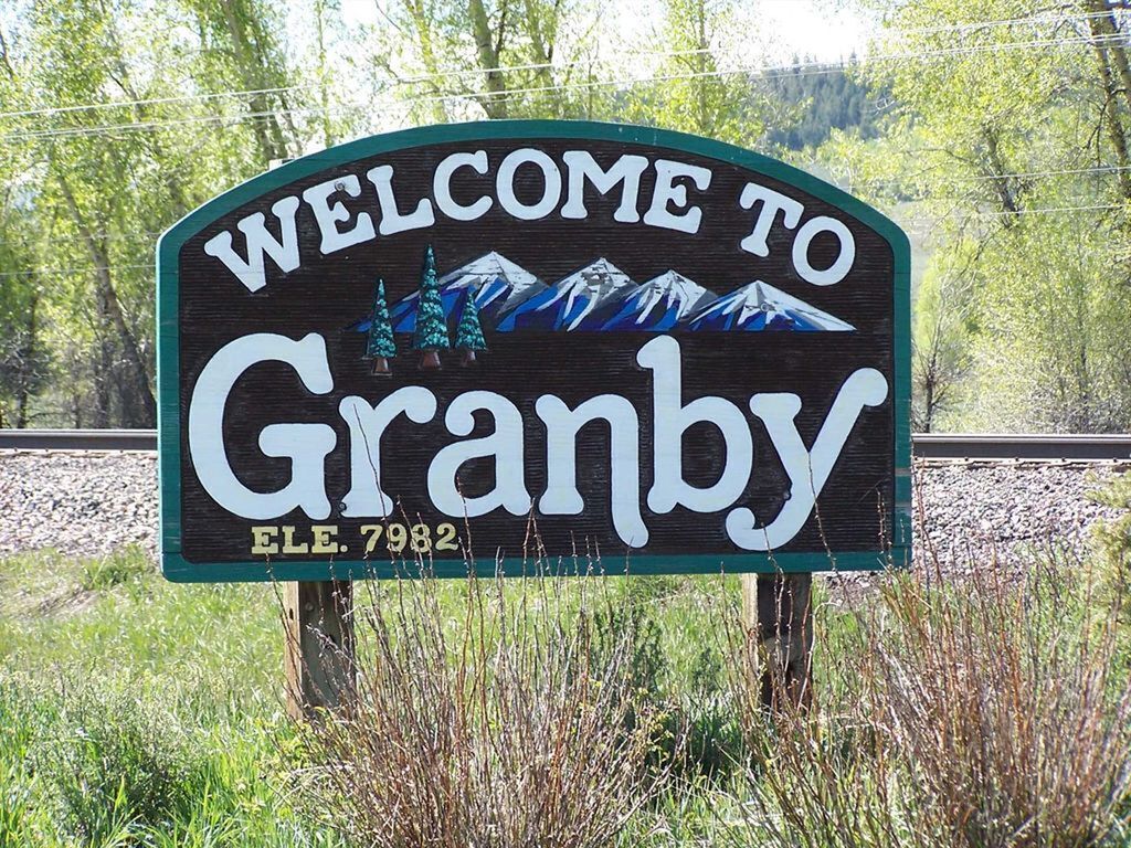 A welcome sign for Granby, featuring a mountain landscape and a Christmas tree.