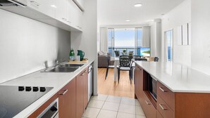 Een moderne keuken met een groot eiland, een eethoek met uitzicht en een balkon met zeezicht.