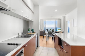 A modern kitchen with a large island, a dining area with a view, and a balcony with a sea view.