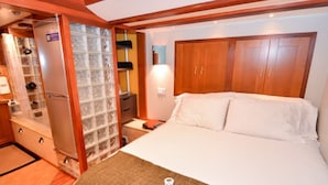 Habitación de hotel con una cama grande, un armario de madera y cabina de ducha de vidrio.