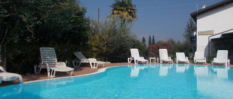 Una piscina al aire libre de temporada, sombrillas, tumbonas