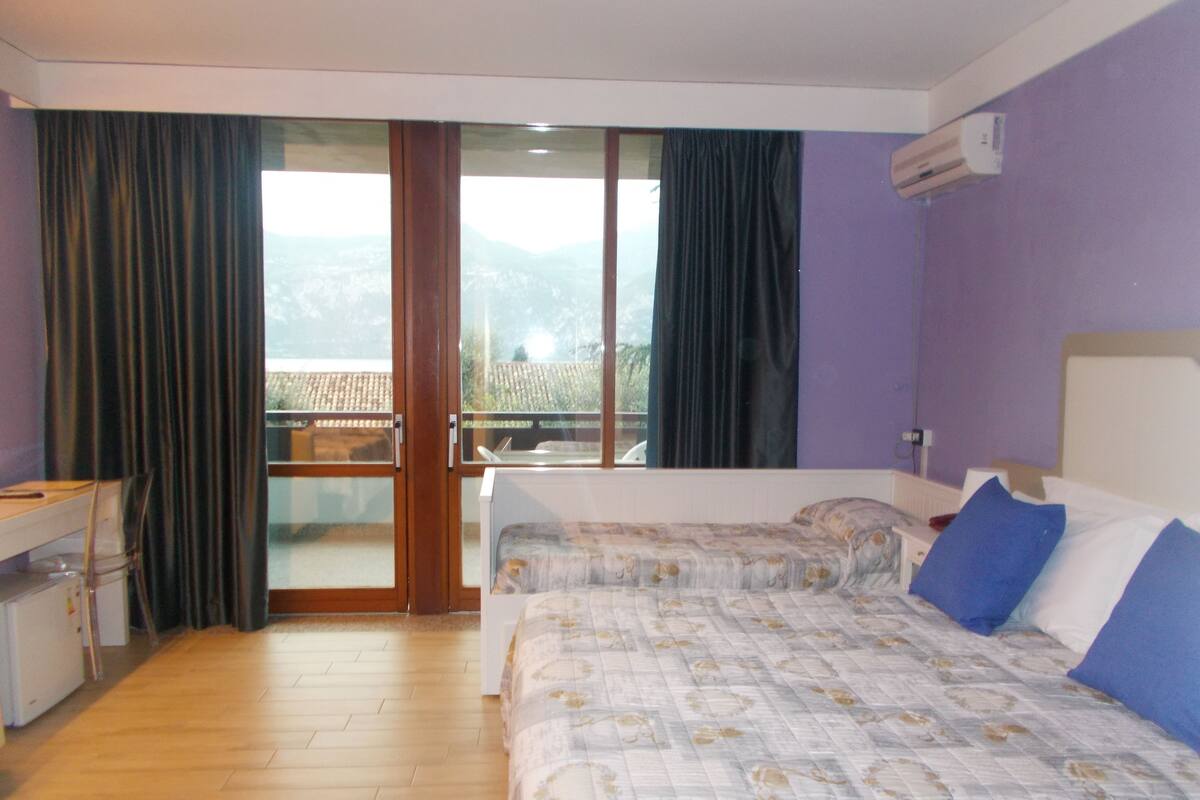 Une chambre d’hôtel avec deux lits, un bureau et une vue sur l’extérieur.