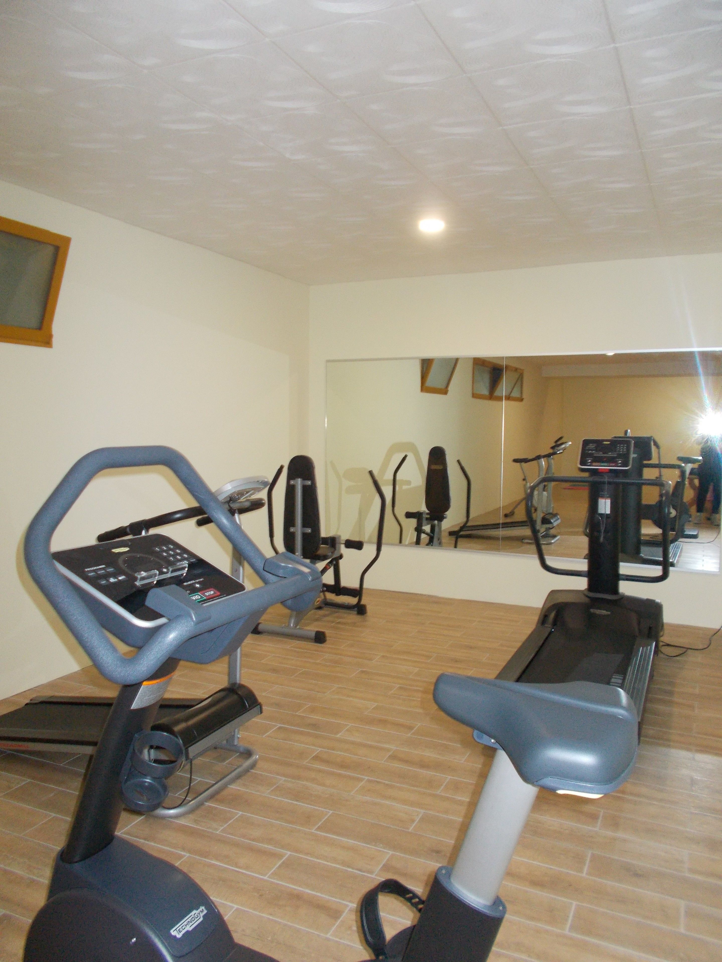 Un gimnasio con equipo de ejercicio, incluyendo una cinta de correr, elíptica y bicicletas estáticas.