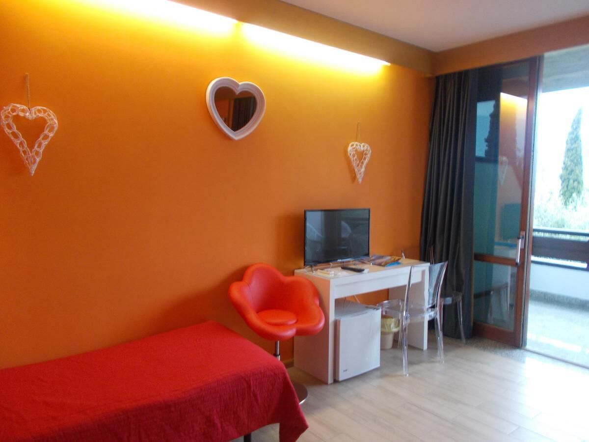 A room with a bed, a desk, a chair, a television, and heart-shaped decorations on the wall.