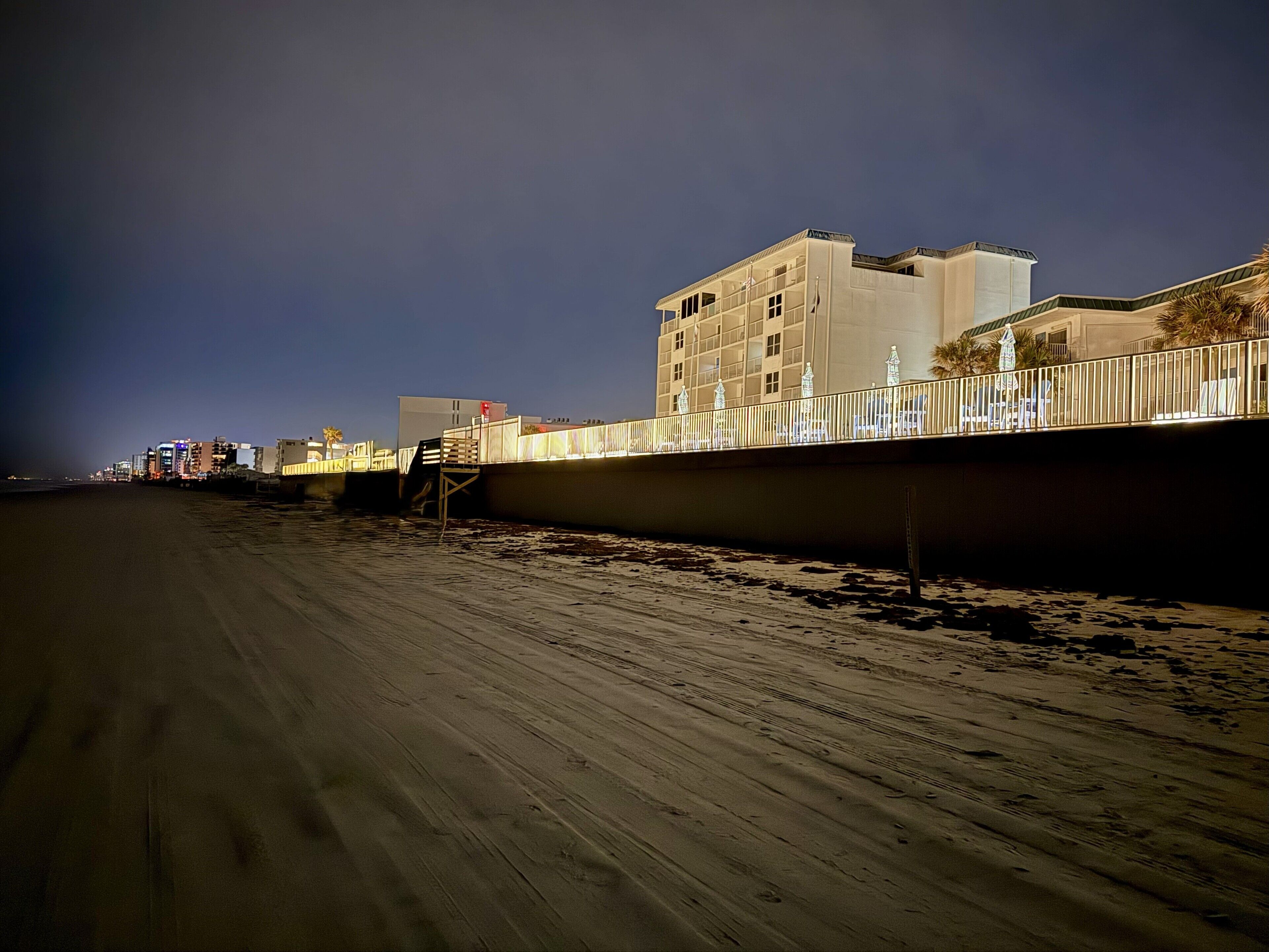 A beachfront hotel with a long, sandy beach and a high-rise building in the background.