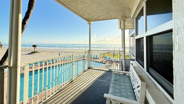 A balcony with a pool, a beach view, and a lounge area. - The Sea Star is an adorable seaside studio with a gorgeous ocean view! (Daytona Beach)