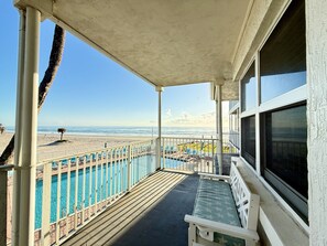 A balcony with a pool, a beach view, and a lounge area. - The Sea Star is an adorable seaside studio with a gorgeous ocean view! (Daytona Beach)