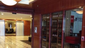Een hotel lobby met een receptiebalie, een ontvangstgedeelte en een winkel in drank met glazen pui.