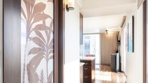 Een modern interieur met een houten vloer, een keuken met aanrecht en kastjes, en uitzicht naar buiten door een raam.