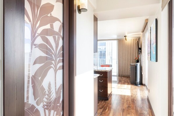 Ein modernes Interieur mit Holzboden, einer Küchenzeile inklusive Arbeitsplatte und Schränken sowie ein Ausblick ins Freie durch ein Fenster.