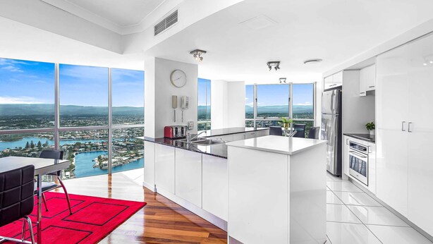 A modern kitchen with a large island, white cabinetry, and a view of a lake and cityscape.