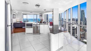 A modern kitchen with a large island, a dining area with a view, and a balcony with city views.