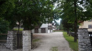 A gravel driveway leading to a stone gate with a sign. - Faloria Mini (Cortina d´Ampezzo)