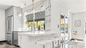 A modern kitchen with a central island, stainless steel appliances, and a bar area with stools.