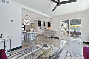 A modern kitchen with a central island, bar stools, and a dining area with a glass table. - Resort Home*The Llama House*Featured on HGTV* Pool and Spa! (Palm Springs)