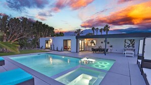 A modern house with a swimming pool, outdoor seating, and a patio.