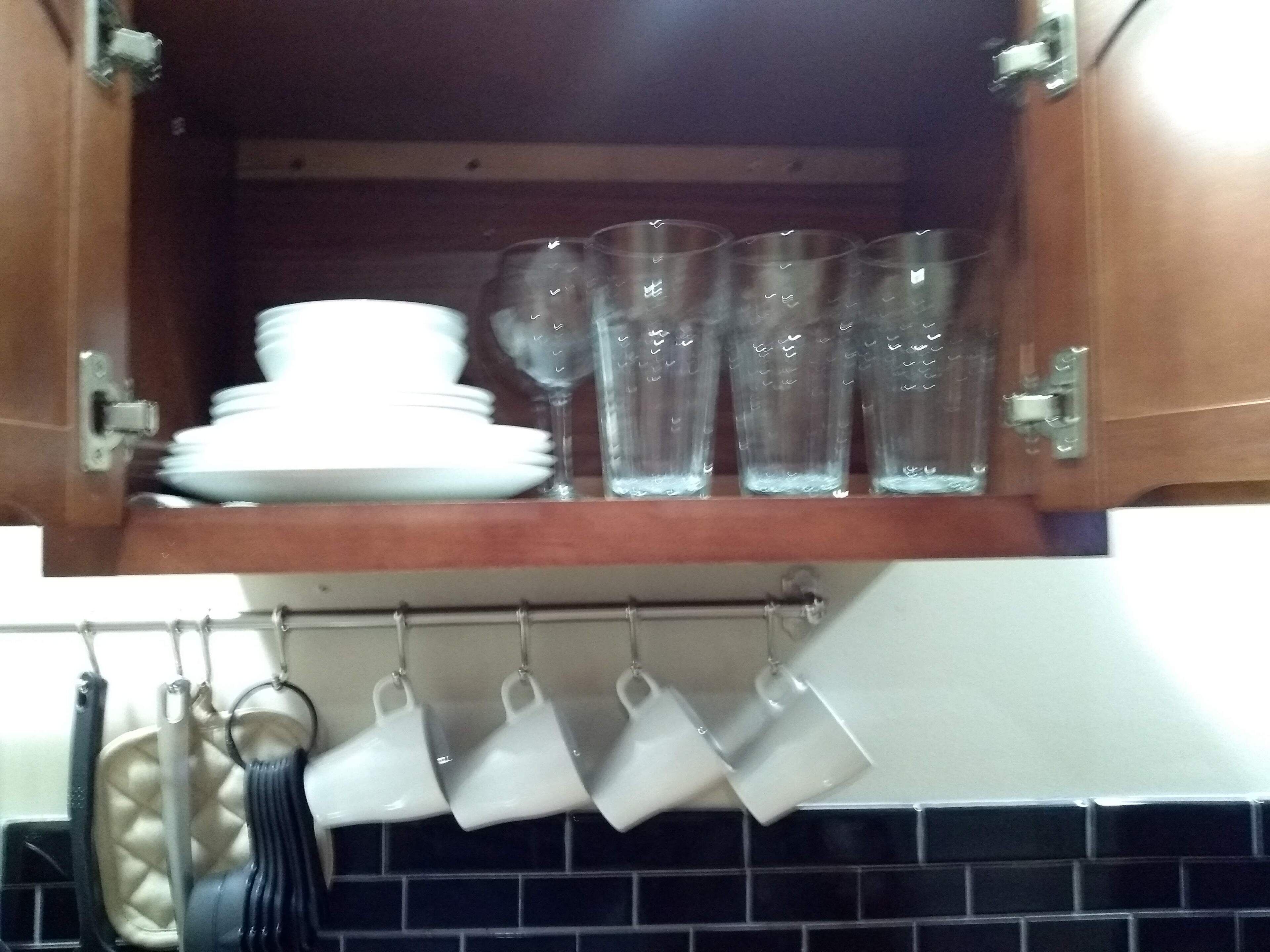 Un meuble de cuisine contenant des assiettes blanches empilées et des verres à boire transparents.