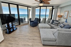 A modern living room with a flat-screen TV, a ceiling fan, and a view of the ocean. - One Ocean Place 605 - Oceanfront in Garden City Beach (Garden City)