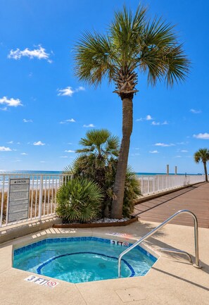 A swimming pool with a palm tree, a wooden deck, and a beach in the background. - One Ocean Place 605 - Oceanfront in Garden City Beach (Garden City)