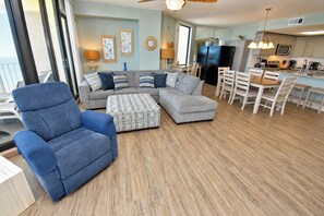 A living room with a sofa set, a blue armchair, and a patterned ottoman. - One Ocean Place 605 - Oceanfront in Garden City Beach (Garden City)