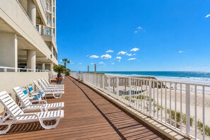 A wooden deck with white sun loungers and a white railing overlooking a beach. - One Ocean Place 605 - Oceanfront in Garden City Beach (Garden City)