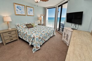 A bedroom with a bed, bedside tables, a TV, and a balcony with a view.