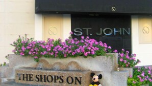 Un edificio con un letrero que dice "THE SHOPS ON EL PASO" y una figura de Mickey Mouse en los escalones.