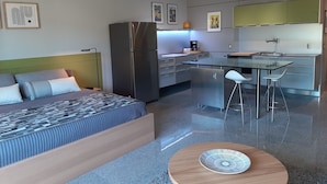 Una habitación de hotel moderna con cama, una pequeña mesa de comedor, una zona de cocina y un baño.