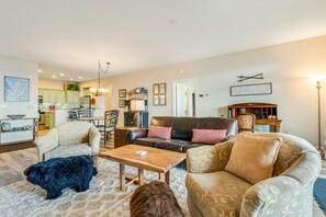 Un salon spacieux avec un canapé, des fauteuils et une table basse. Il y a un chien dans la pièce.