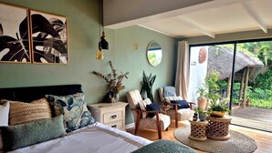Una camera da letto con un letto grande, un comodino, una sedia, uno specchio e vista sull'esterno.