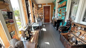 A room with a wooden floor, a table with various items, a chair, and a door leading to another room. - Heritage Classic Inn B&B - Room 1 (Hunter River)