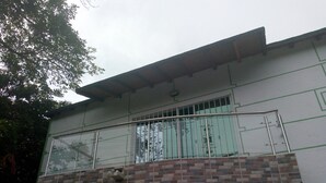 A two-story building with a balcony on the second floor, featuring a metal railing and a window with bars. - apartamentos por dias el TUCAN (Santa marta)