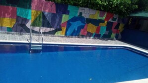 A swimming pool with a colorful mural on the wall and a tiled edge. - apartamentos por dias el TUCAN (Santa marta)