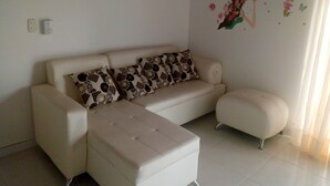 A modern living room with a sofa, ottoman, and decorative wall stickers. - apartamentos por dias el TUCAN (Santa marta)