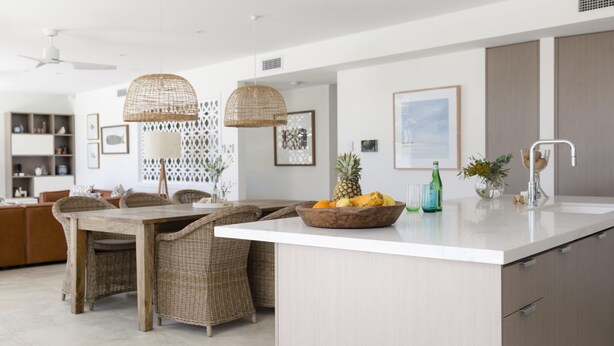 A modern kitchen with a central island, wicker furniture, and a dining area. - Paddle on Seven Mile (LENNOX HEAD)