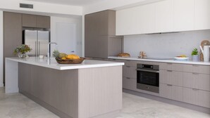 A modern kitchen with a central island, stainless steel appliances, and light wood cabinetry. - Paddle on Seven Mile (LENNOX HEAD)