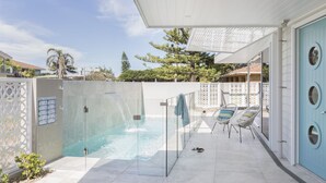 A private pool area with a glass-enclosed hot tub, two lounge chairs, and a door with circular windows. - Paddle on Seven Mile (LENNOX HEAD)